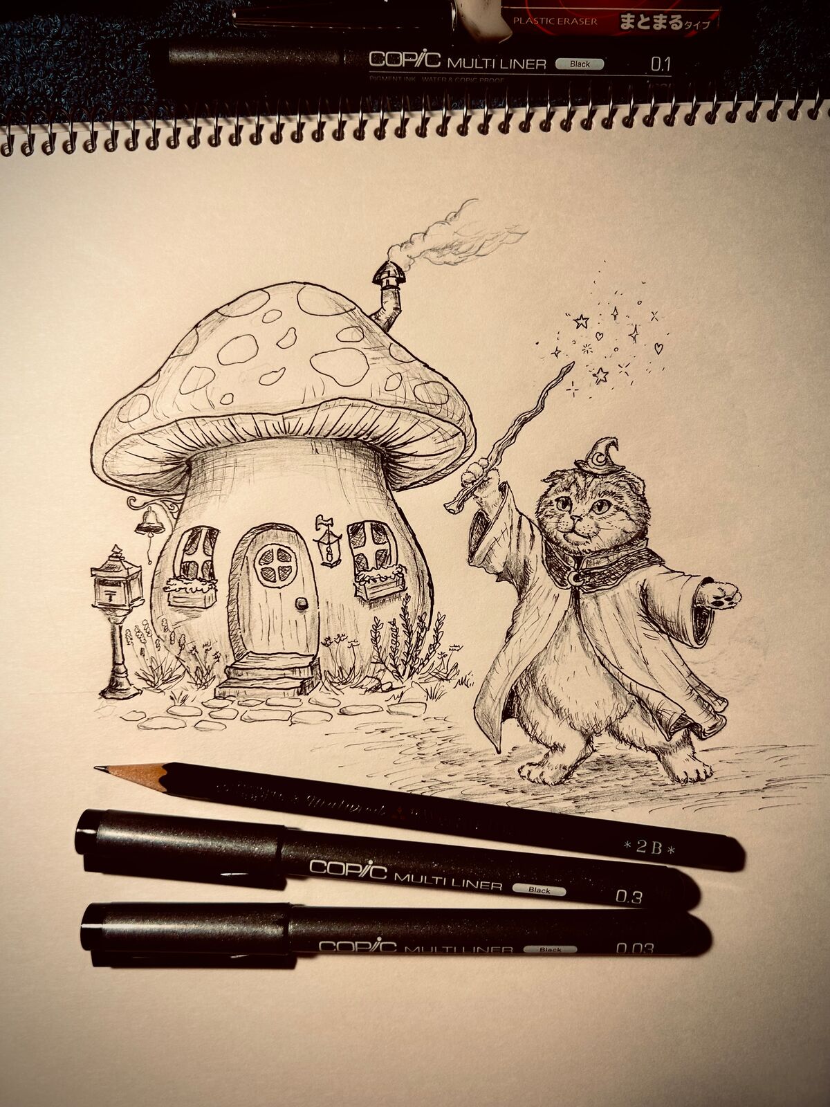 煙突から煙の立ちのぼる、水玉模様の大きなキノコの家のイラスト。丸いドアと花壇つきの窓、郵便受けと石畳の小道が前に続き、その横では、とんがり帽子とマントを着た二足歩行のスコティッシュフォールドの猫が、枝の魔法の杖を高く掲げて星やハートのきらめきを呼び出している。